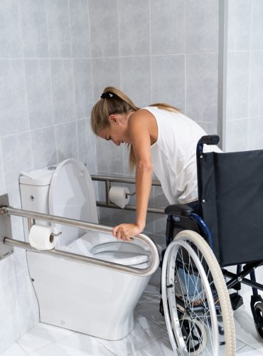 woman getting up with her arms from wheelchair toilet